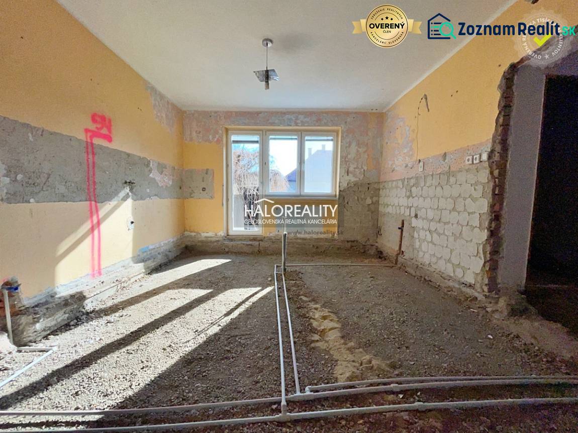 The interior of a family house under renovation with visible brick walls and a window.