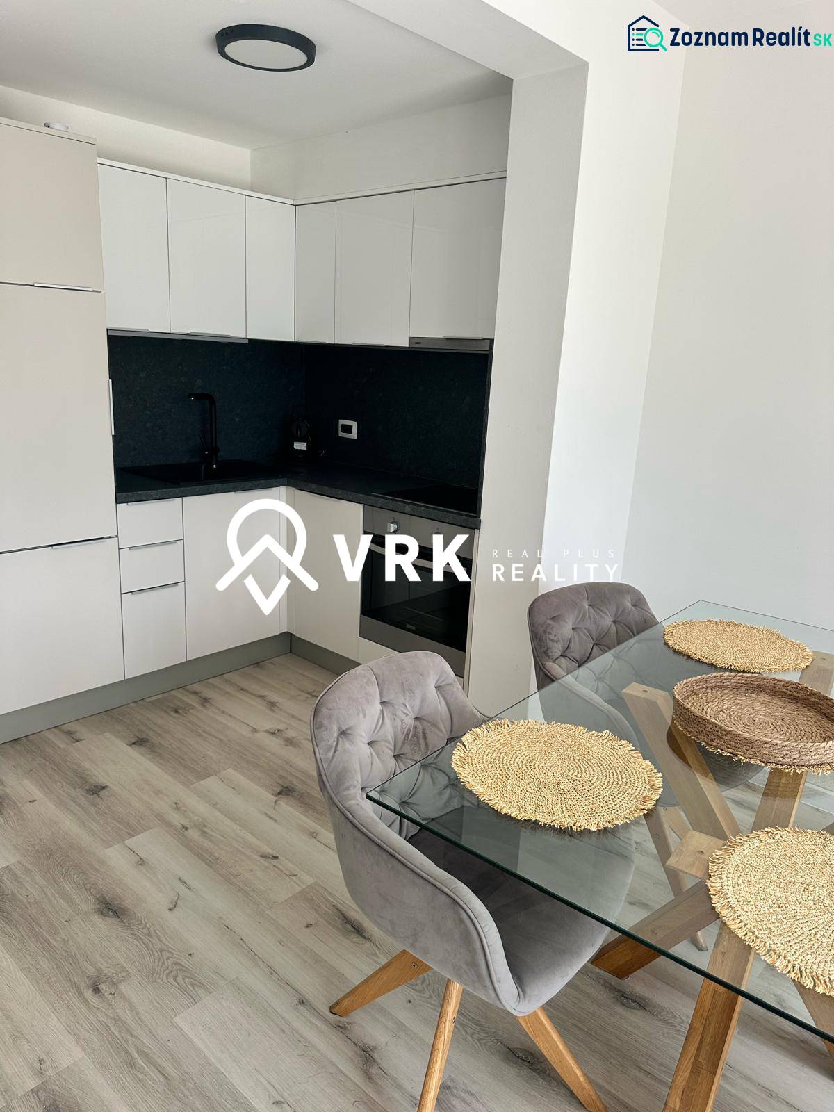 Recreational apartment with a kitchen, glass table, and wooden decor flooring.