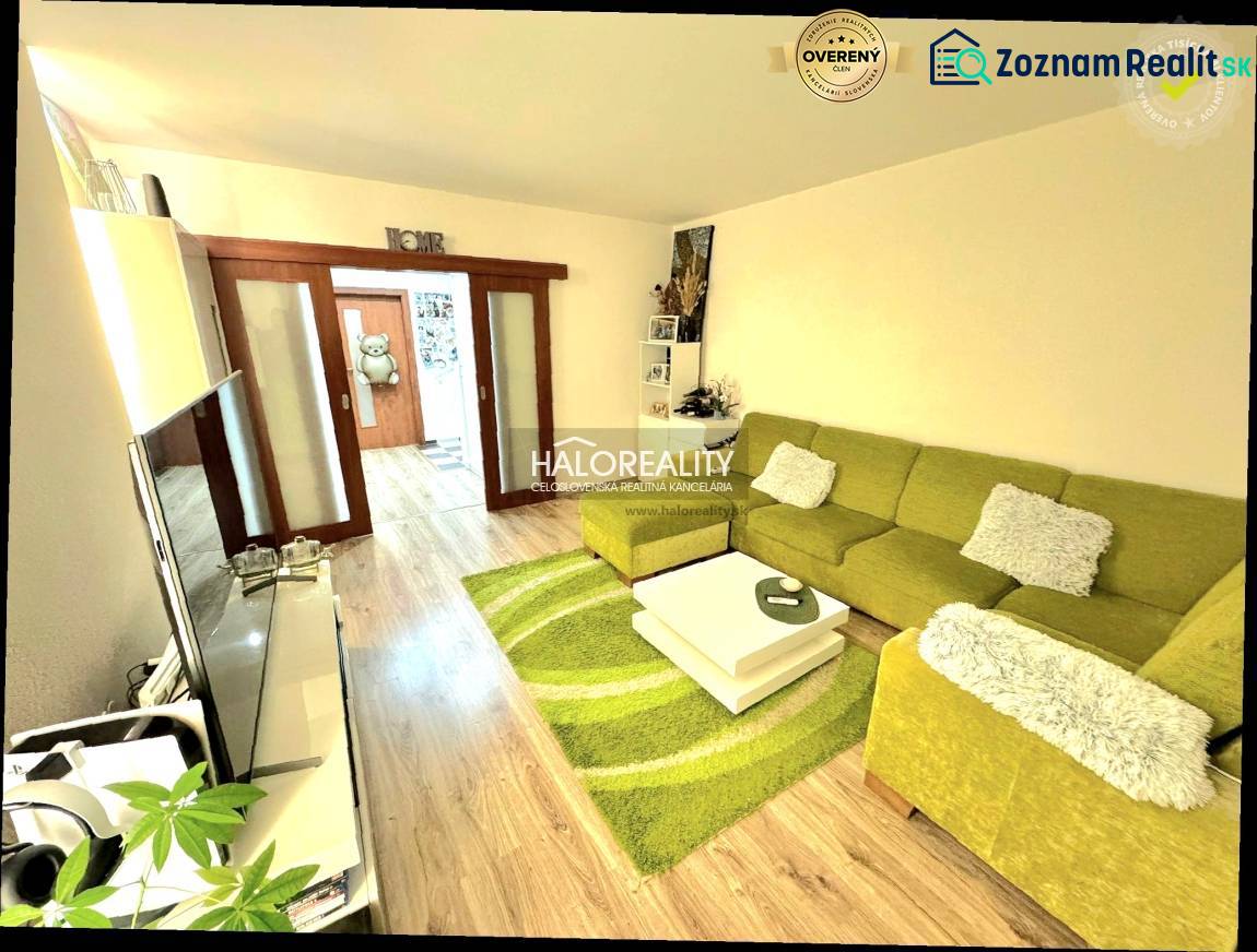 Living room with a sofa and wood-patterned flooring in a three-room apartment.