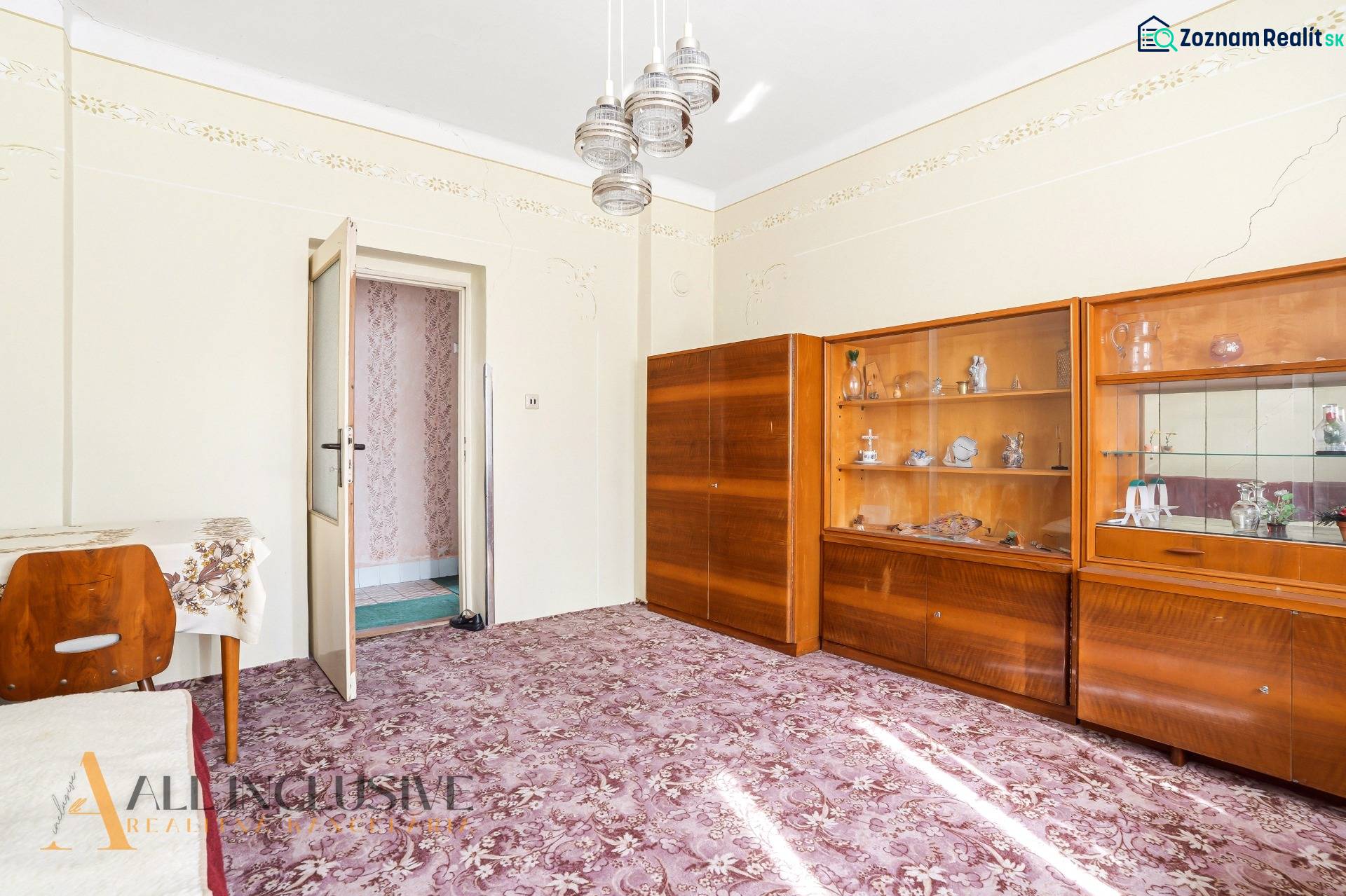 A room in a family house with display cabinets, a table, and a patterned carpet.