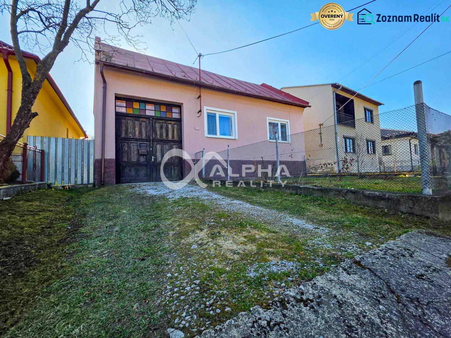 A family house in Spišské Vlachy with a wooden gate and a sloping access road.