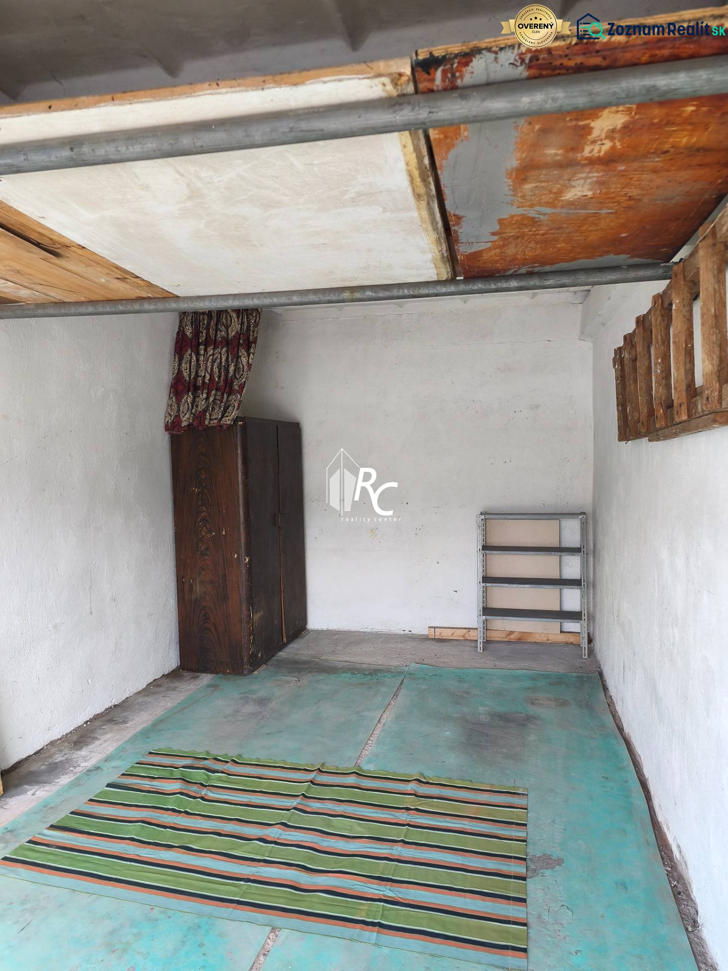 The interior of the garage includes a wooden cabinet, a rug, and empty shelves.