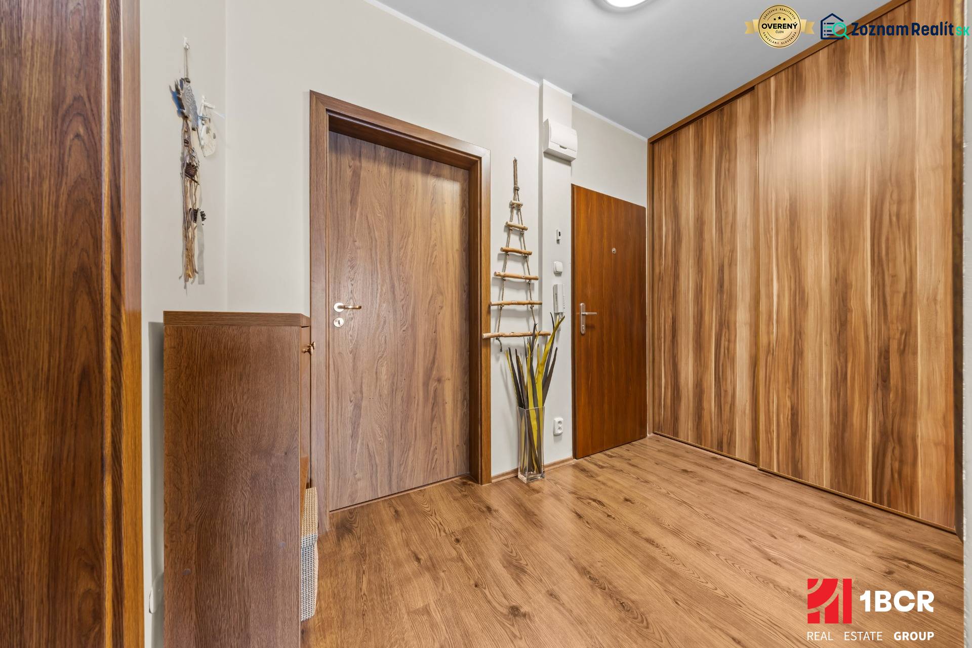 A hallway with a wooden decor floor in a 3-room apartment, built-in wardrobes and decorations.