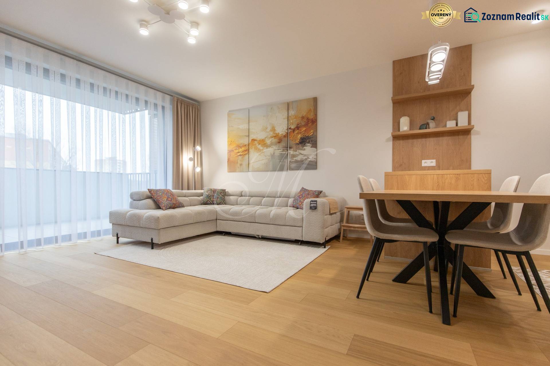 Living room in a 2-room apartment with a sofa, dining table, and wooden decor flooring.