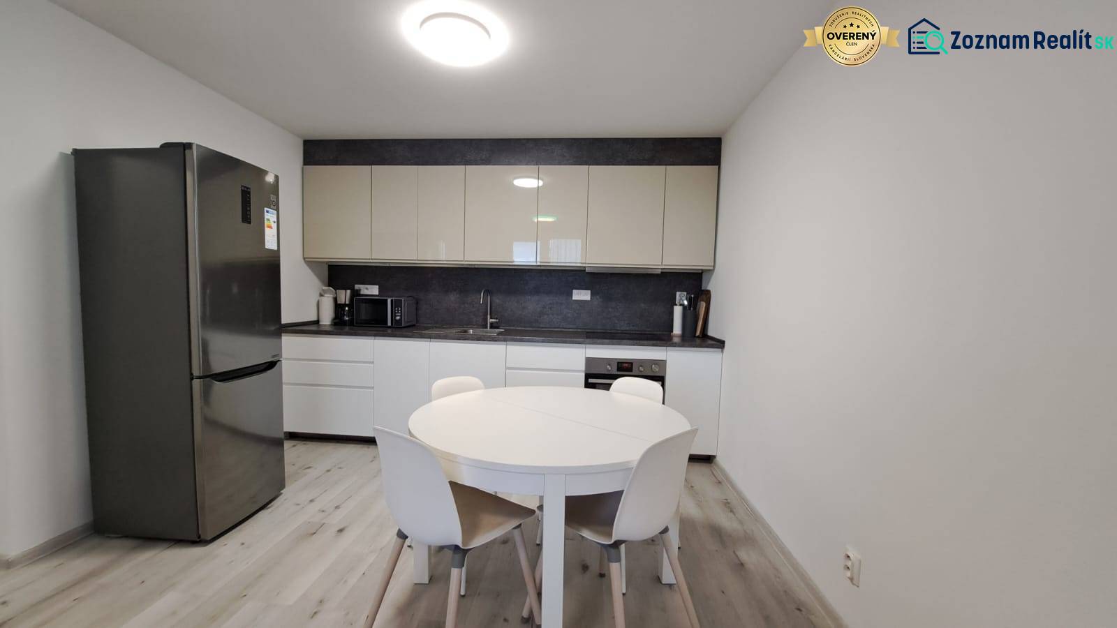 A kitchen in a family house with a refrigerator, a round table, and a floor with a wooden decor.
