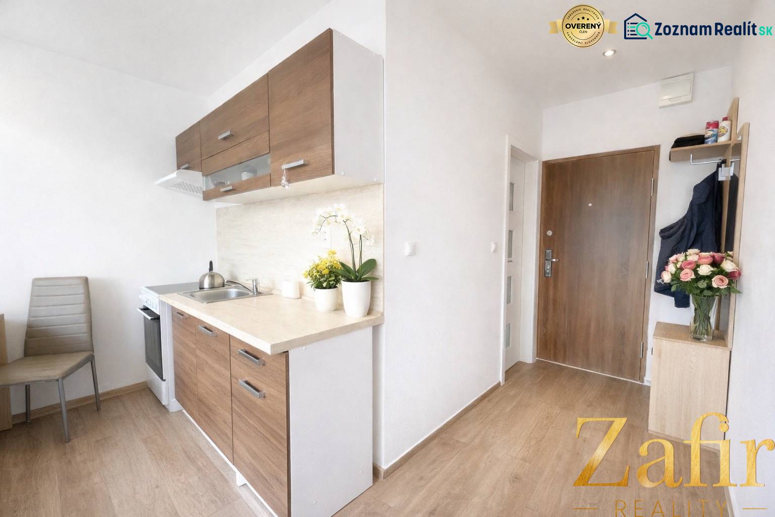 A kitchen with wooden decor and entrance door in a studio apartment.
