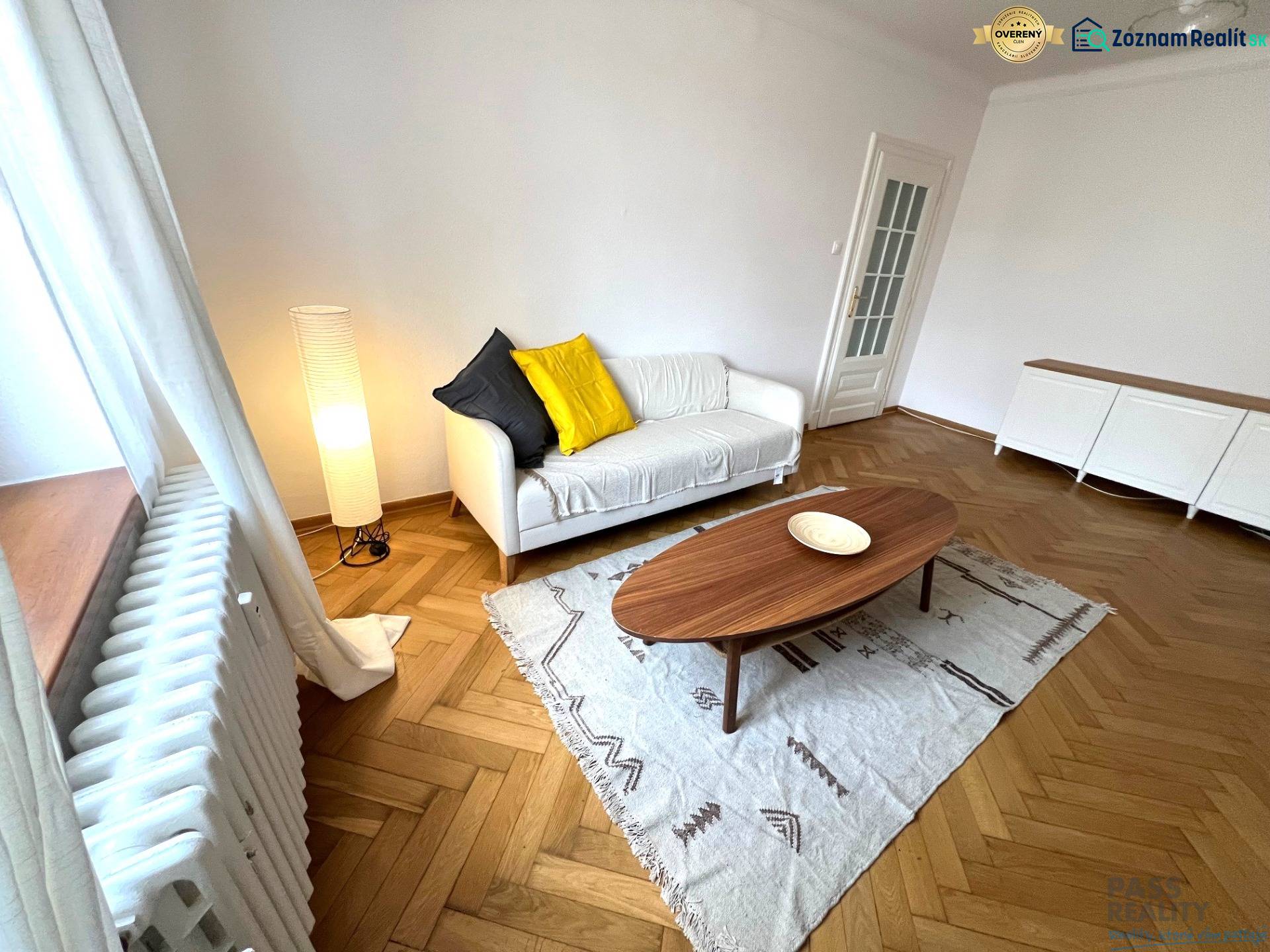 Living room with wood-patterned flooring, sofa, and table in a two-room apartment.