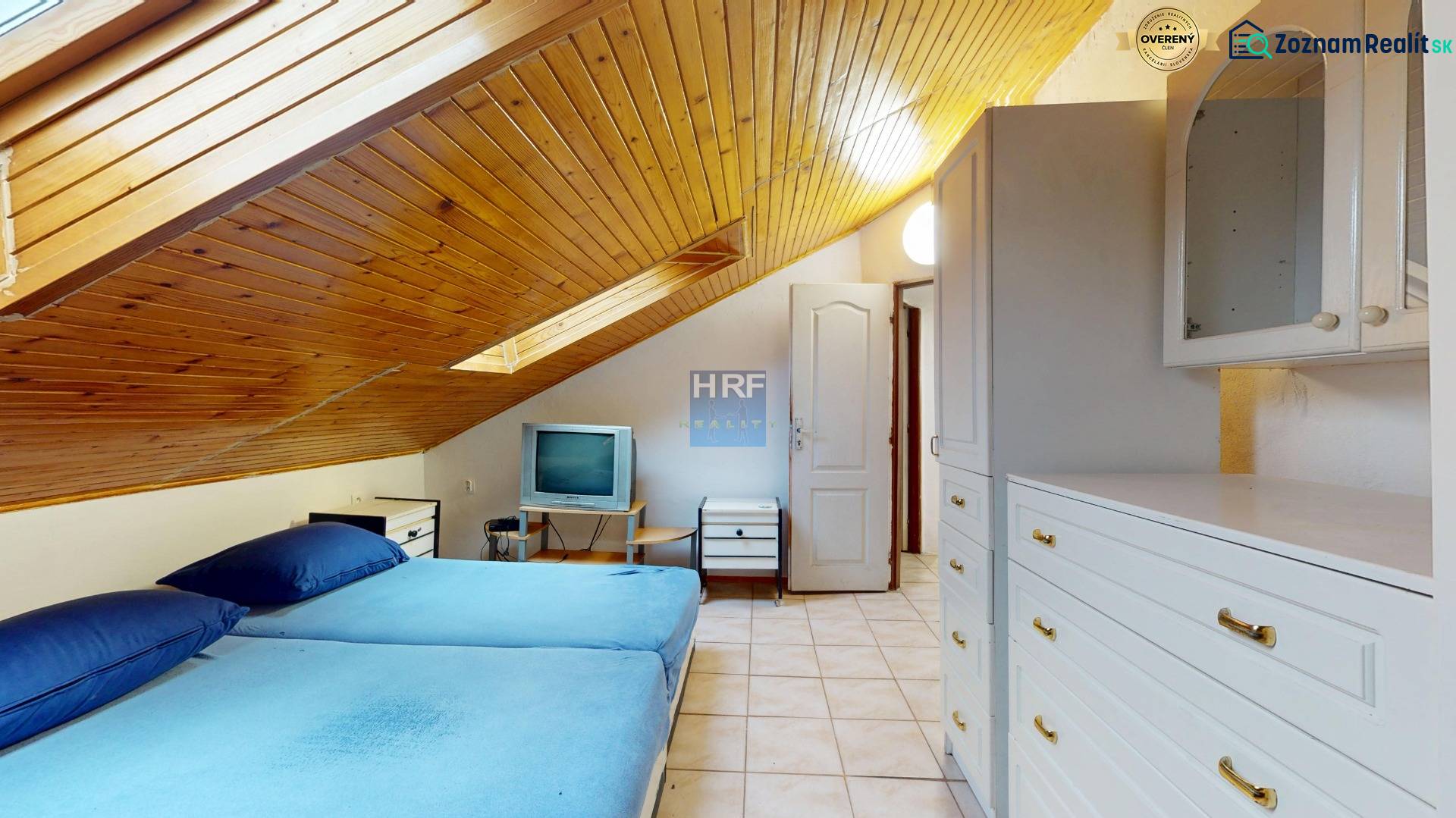 A space with a slanted wooden ceiling, a bed, and furniture in a 3-room apartment.