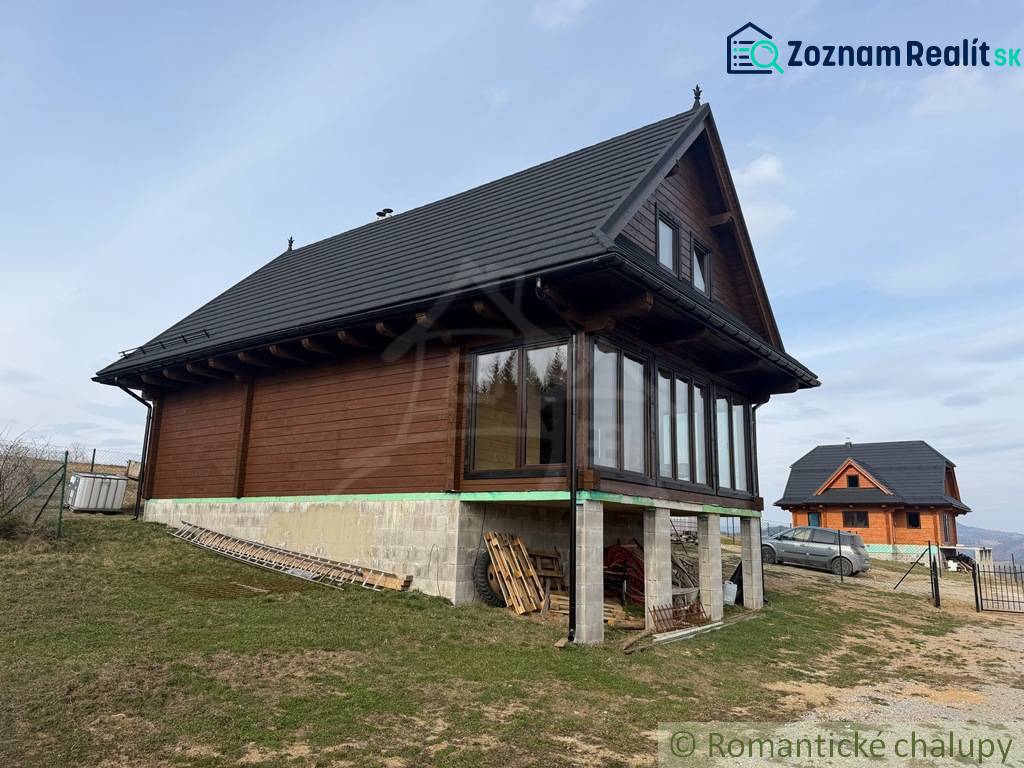The family house in Lom nad Rimavicou is wooden with a black roof and large windows.