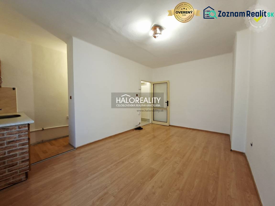 A studio apartment with a wooden floor and simple furnishings.