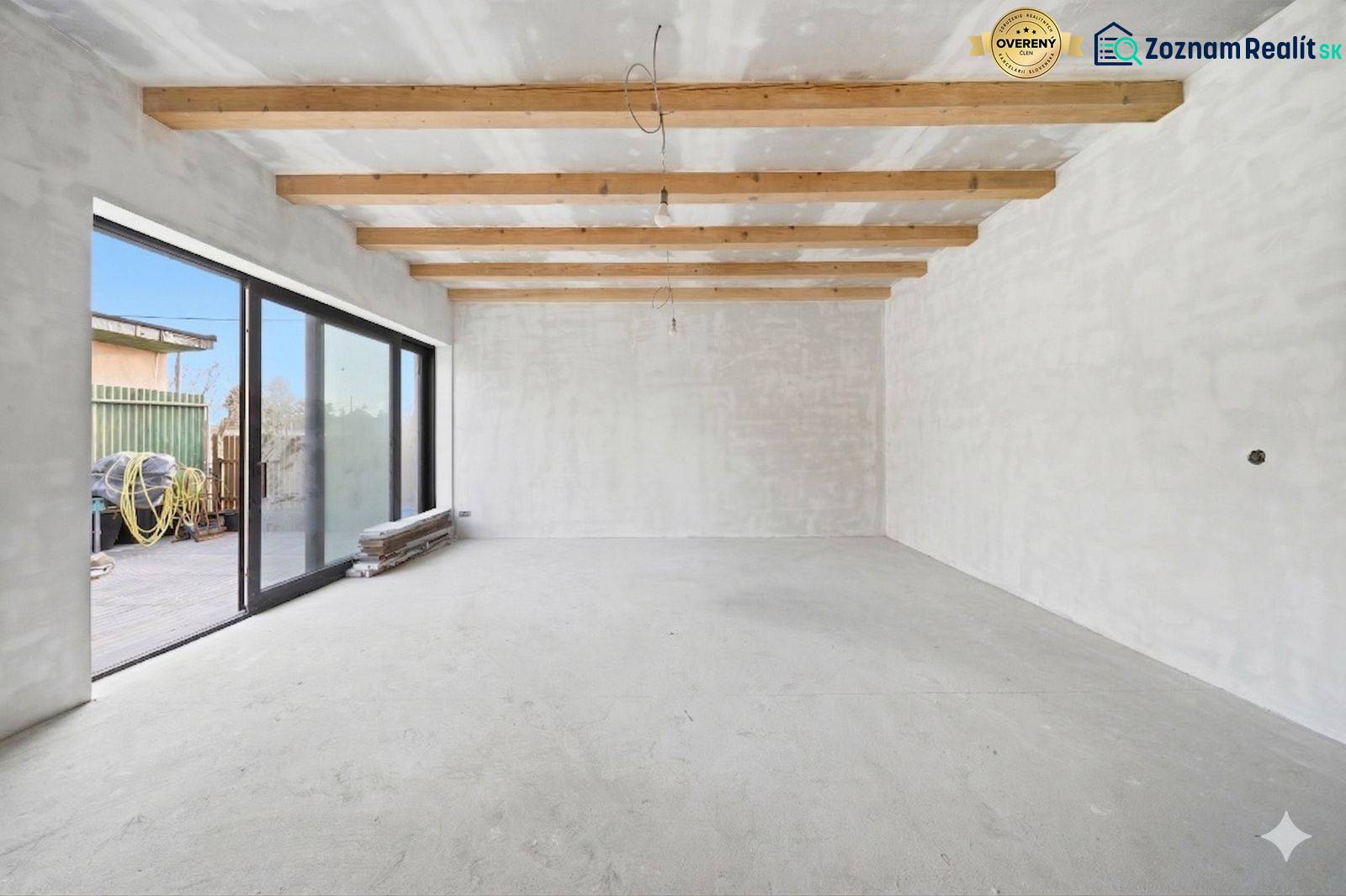 Spacious room in a family house with wooden beams and large glass doors.