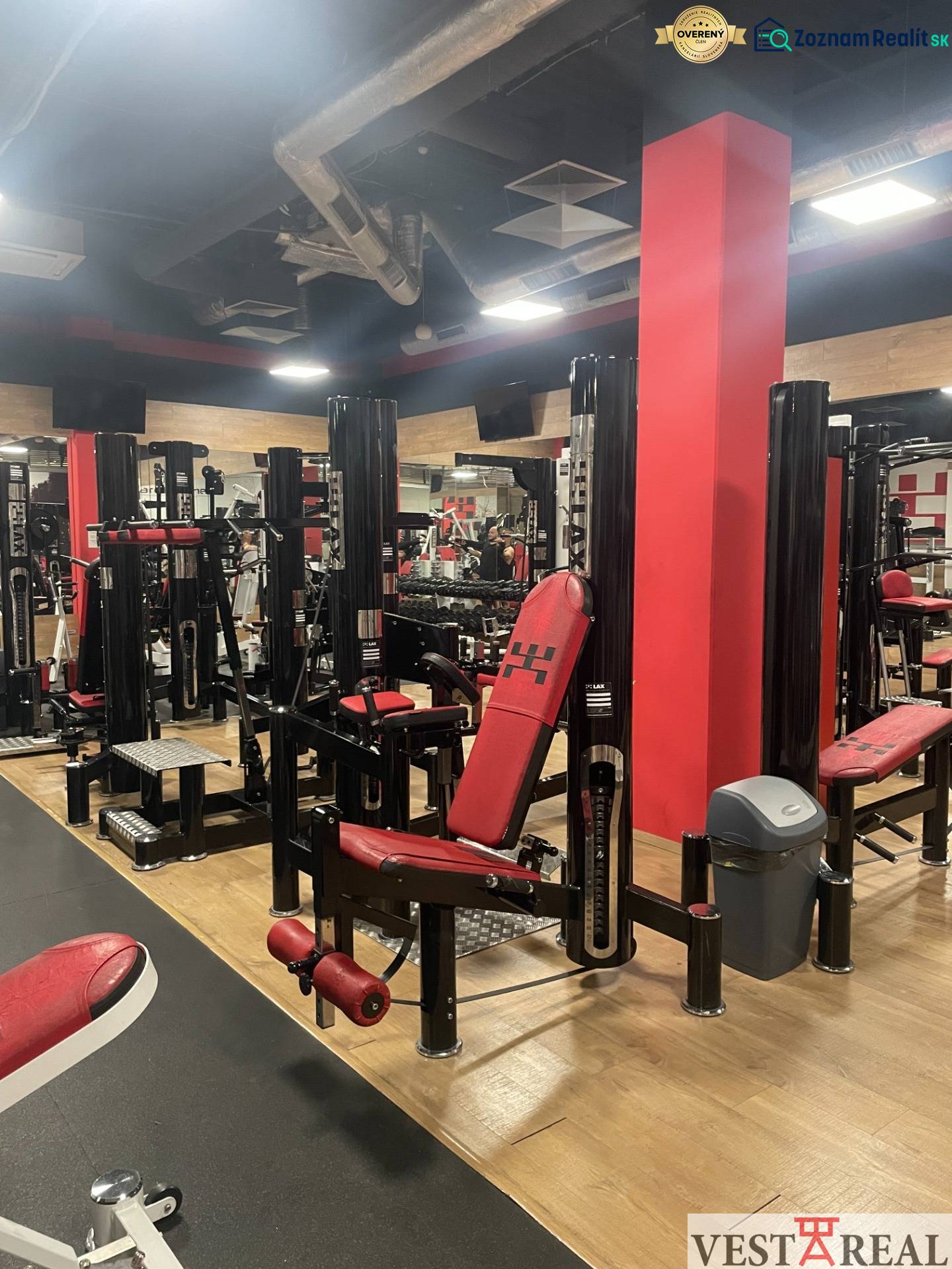 Strength training machines in commercial spaces with wood-patterned flooring.