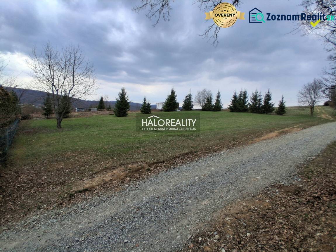 A residential building plot in Prešov with grass, trees, and a gravel road.