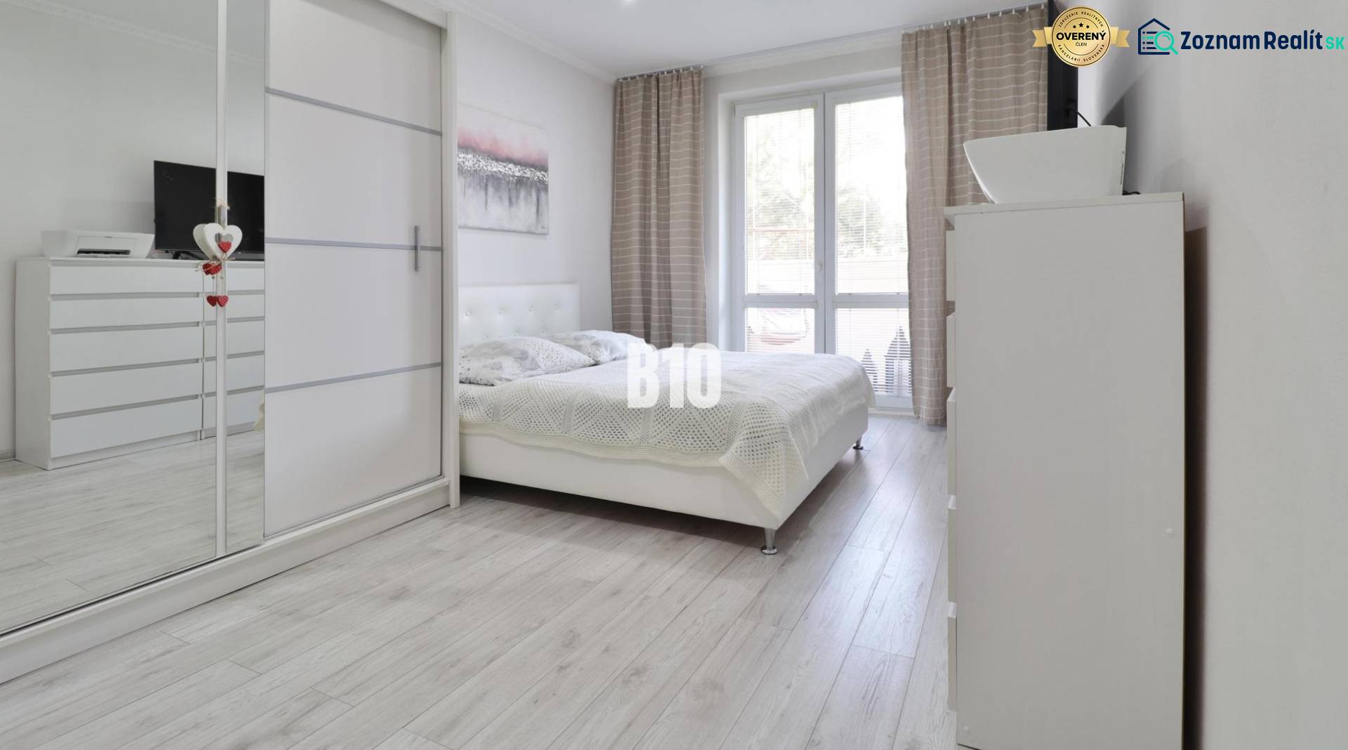 A bright bedroom with a large bed, wardrobe, and wooden decor flooring in a 2-room apartment.