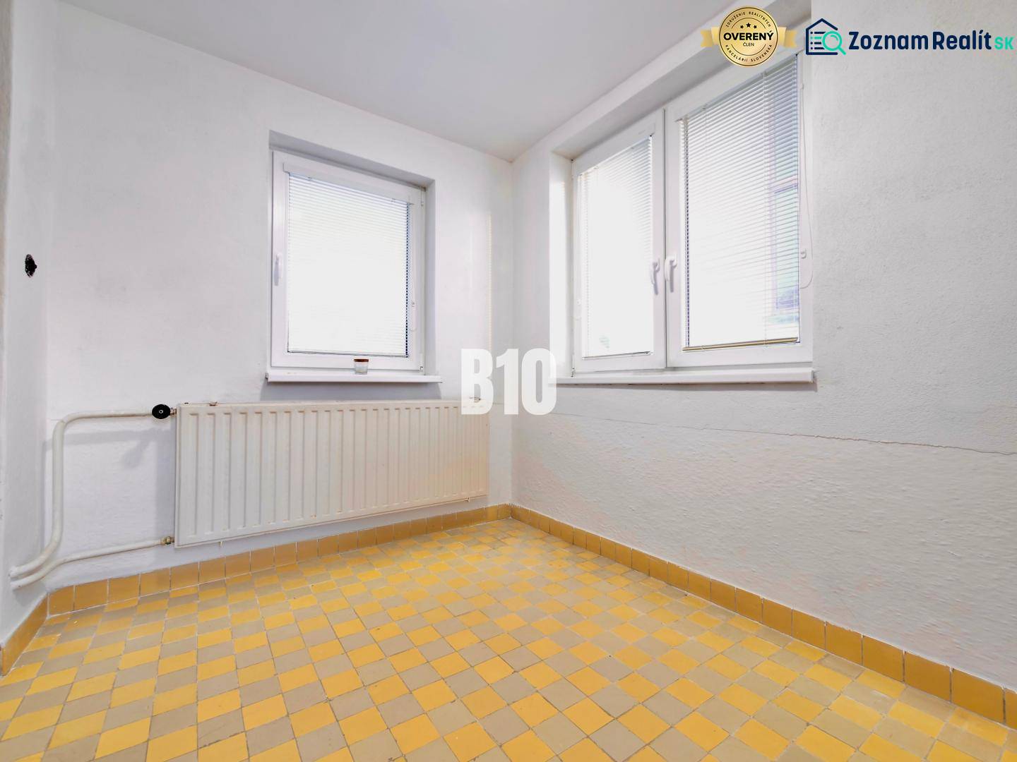 White wall, windows, radiator, and yellow tiled floor in a family house.