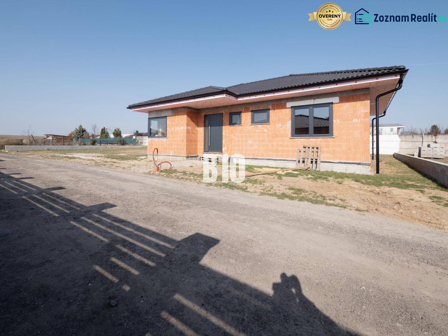 A family house under construction in Veľký Lapáš with a simple facade on an unkempt plot.