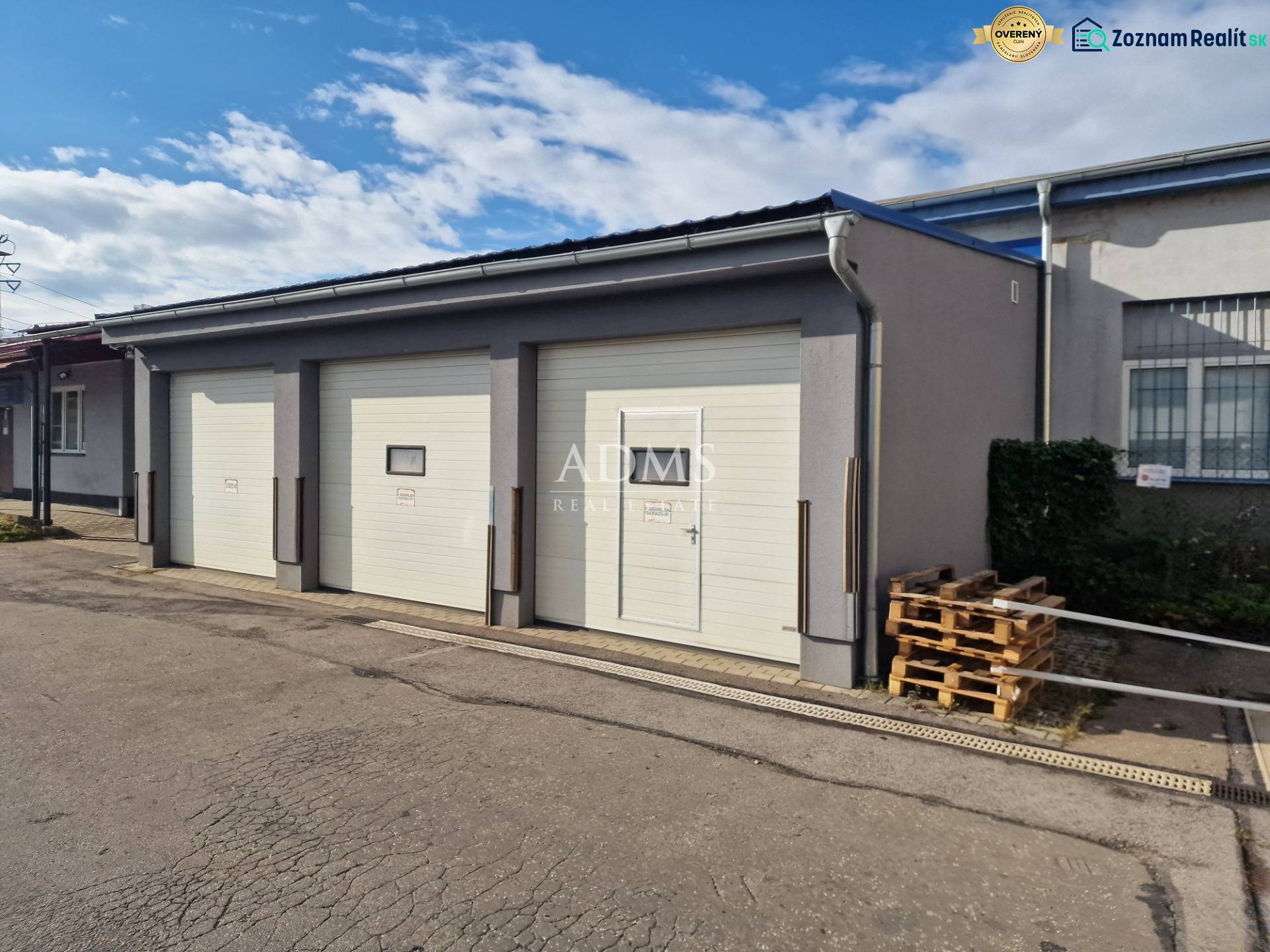 Warehouses and halls in Žilina with sectional garage doors and pallets next to the building.