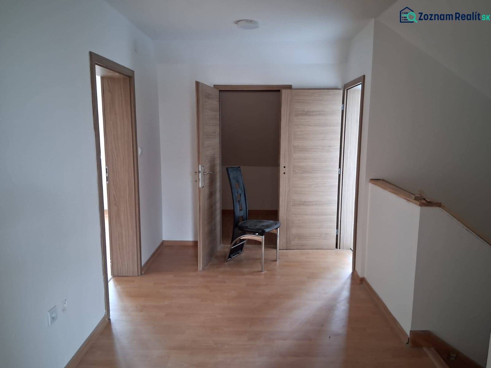 A room in a family house with a wooden decor floor and three wooden doors.