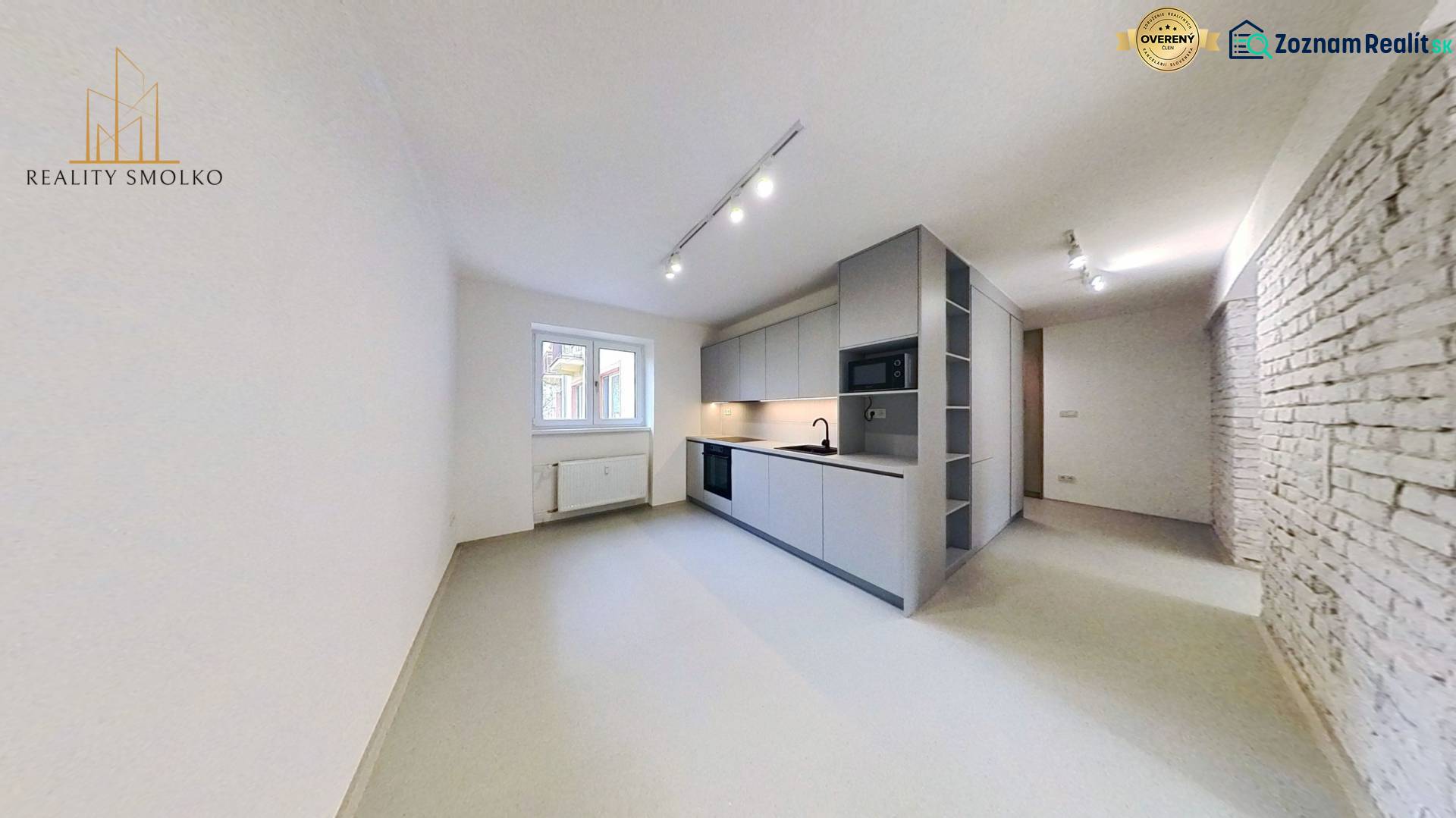 A bright kitchen in a 2-room apartment with a white brick wall and built-in lighting.