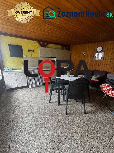 Covered terrace in a cabin with wooden decor, comfortable furniture, and a table for relaxation.