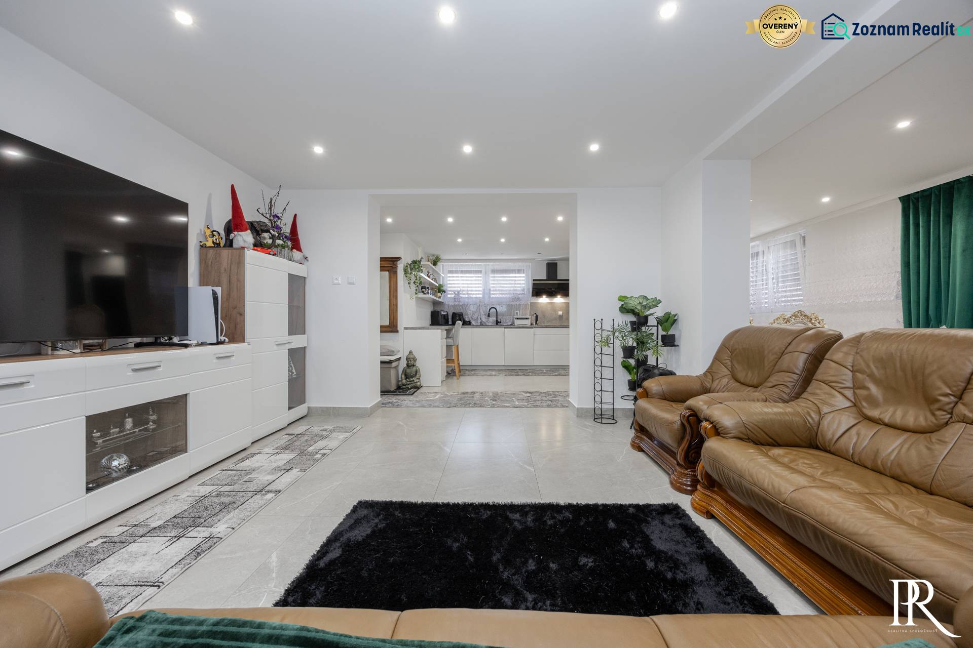 Living room with leather furniture, tiled floor, and kitchenette in a family house.