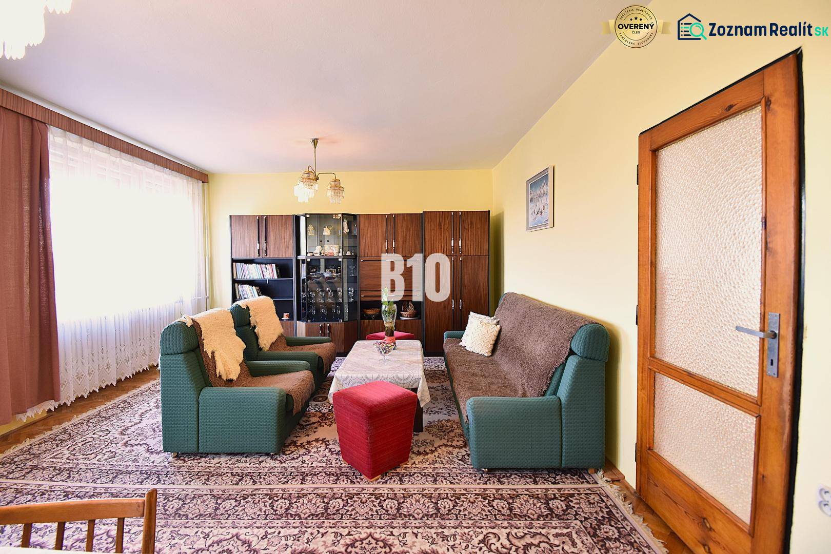 Living room in a family house with sofas, armchairs, a display cabinet, and a carpet.