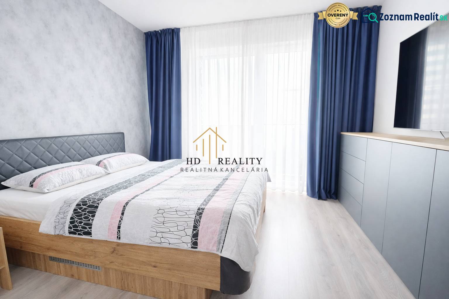 A bedroom in a 3-room apartment with a bed, blue curtains, and a dresser.