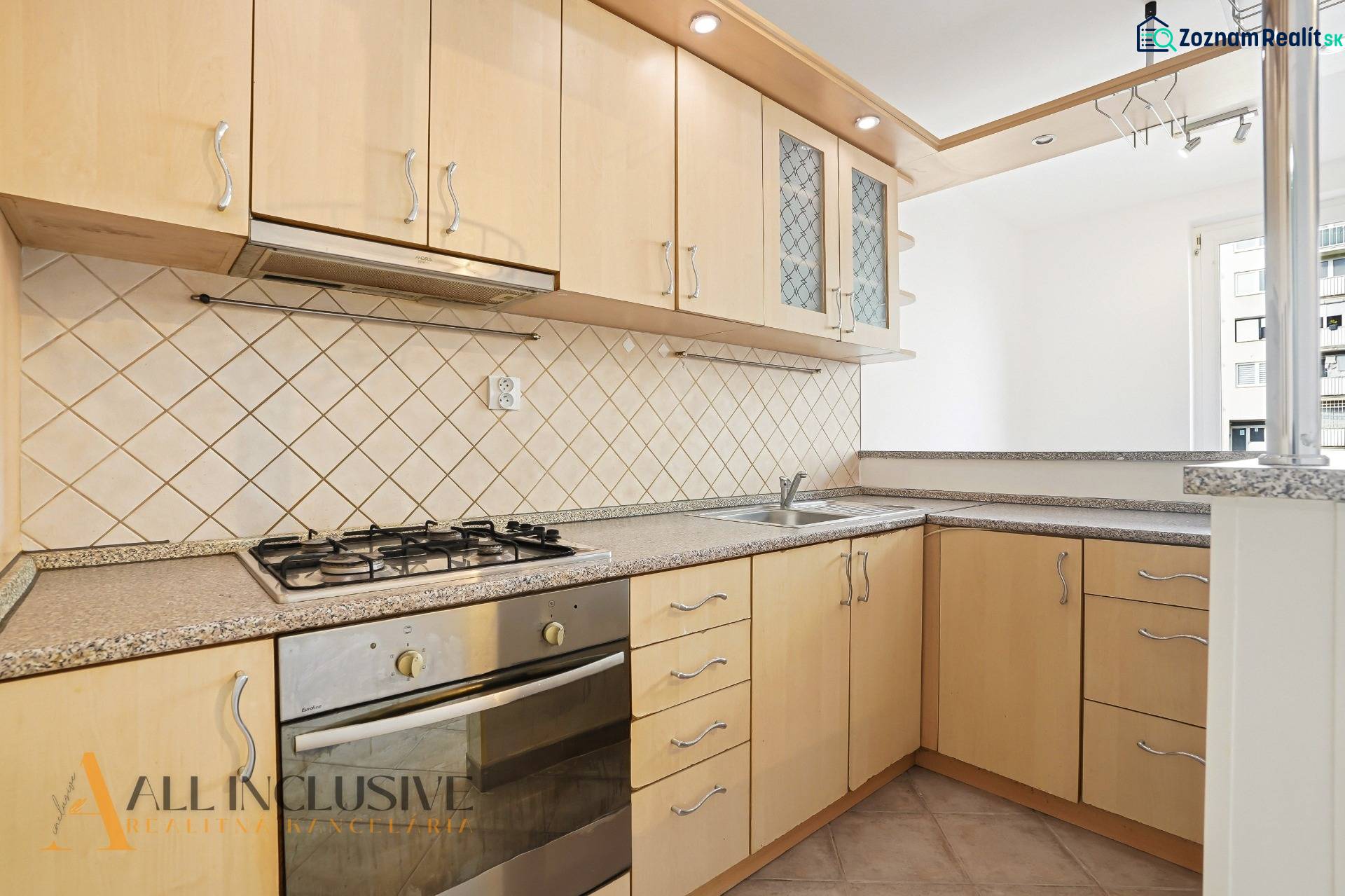 A kitchen in a 2-room apartment with a gas stove and light kitchen cabinets.