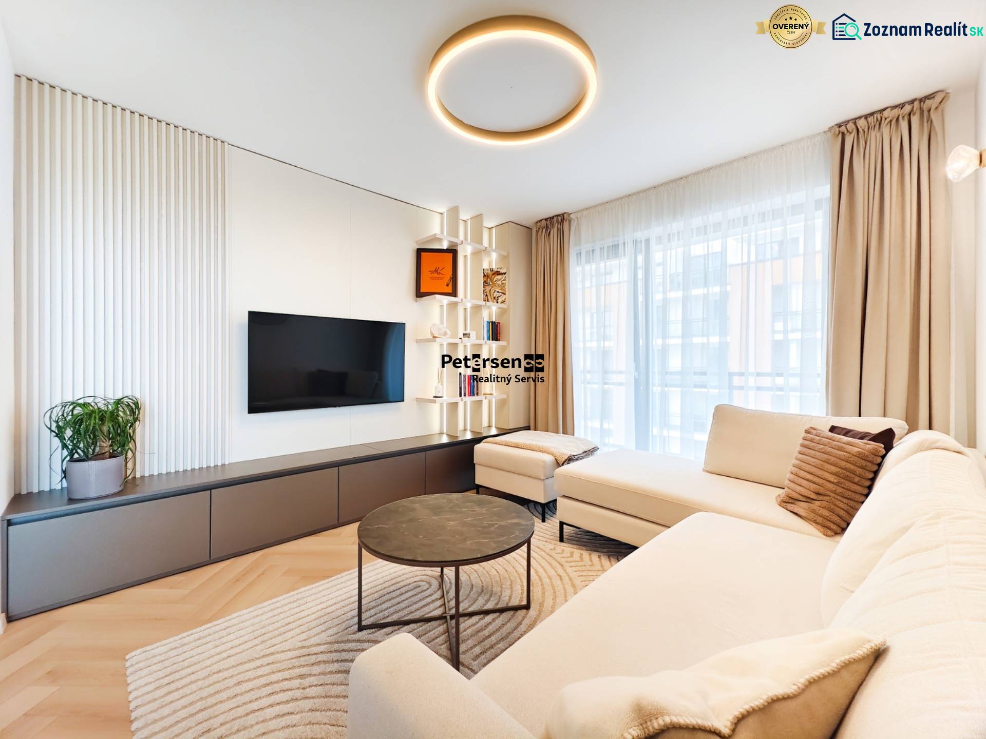 Living room in a 2-room apartment with a sofa, television, and a wooden decor floor.