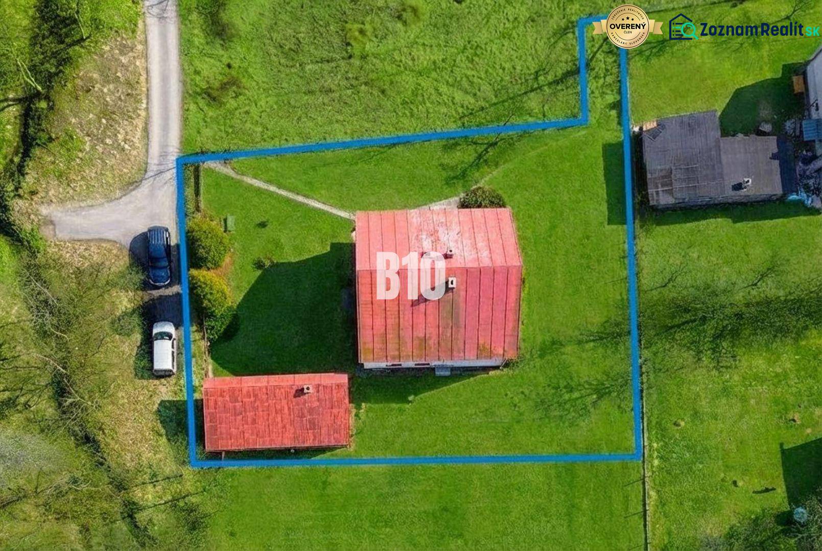 A family house in Raková with a fenced plot and adjacent buildings surrounded by greenery.