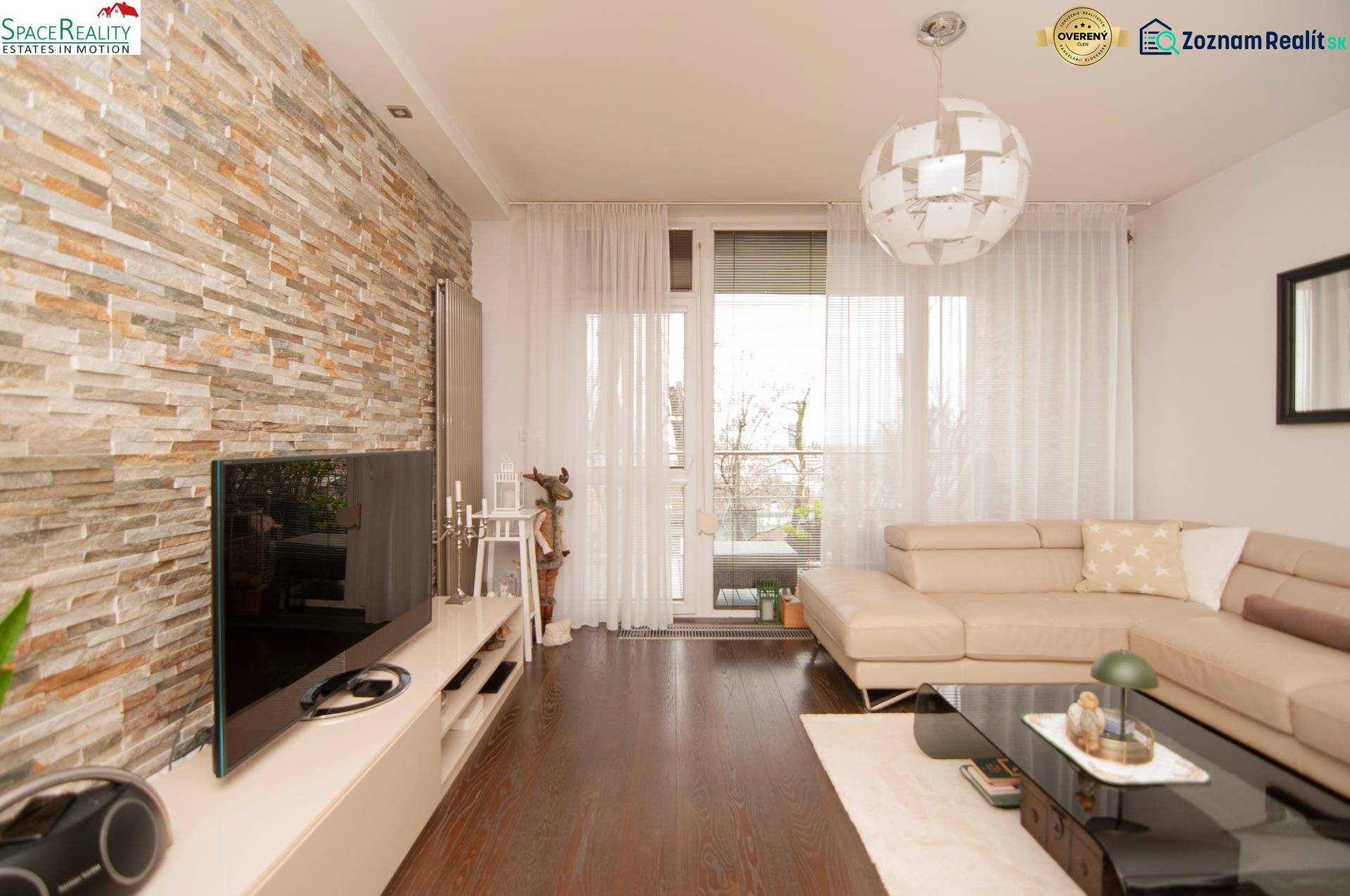 Living room in a two-room apartment with a stone wall and a wooden decor floor.