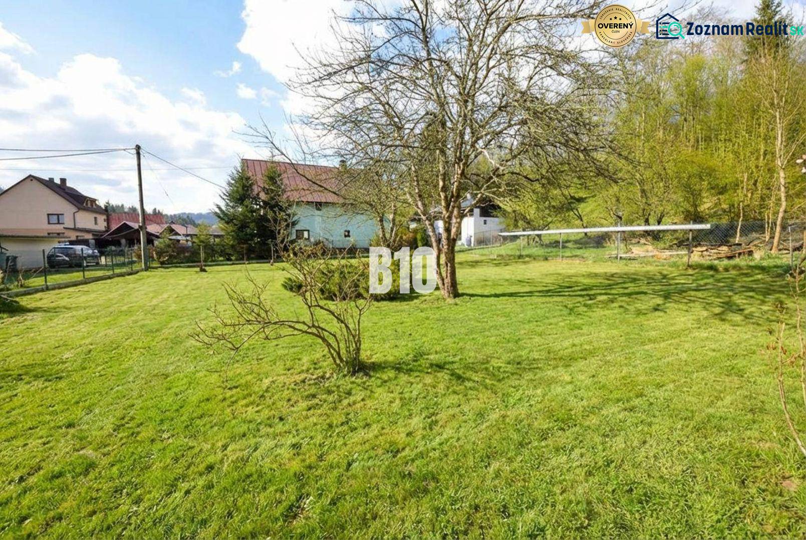 A grassy plot with several trees in the residential area of the village Raková.