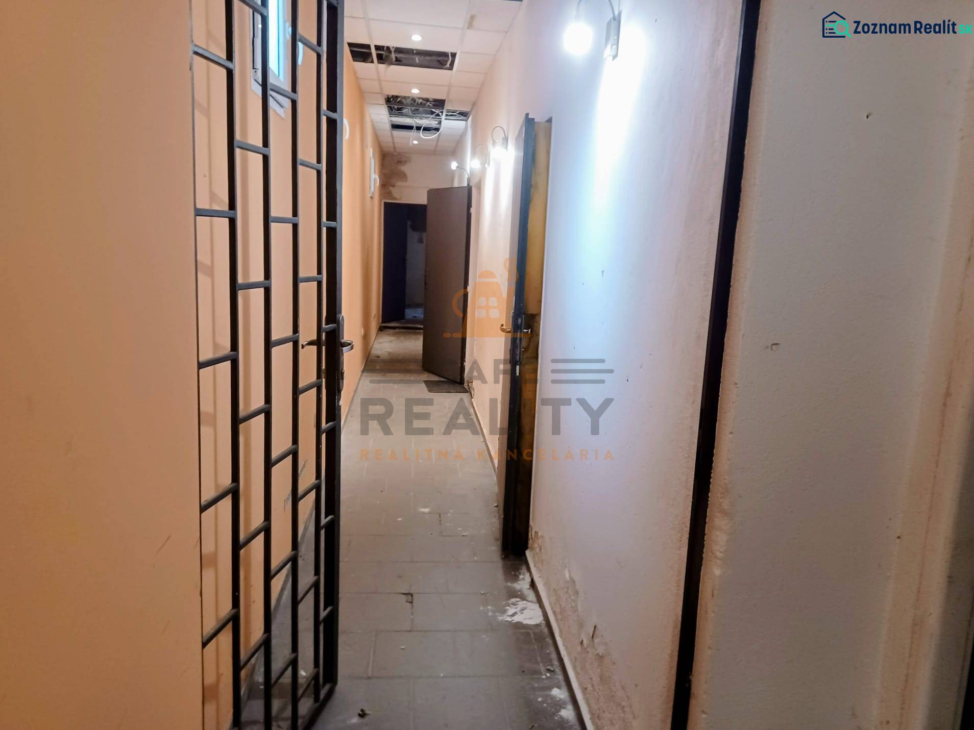 A narrow corridor with a metal grid and lighting in commercial premises.