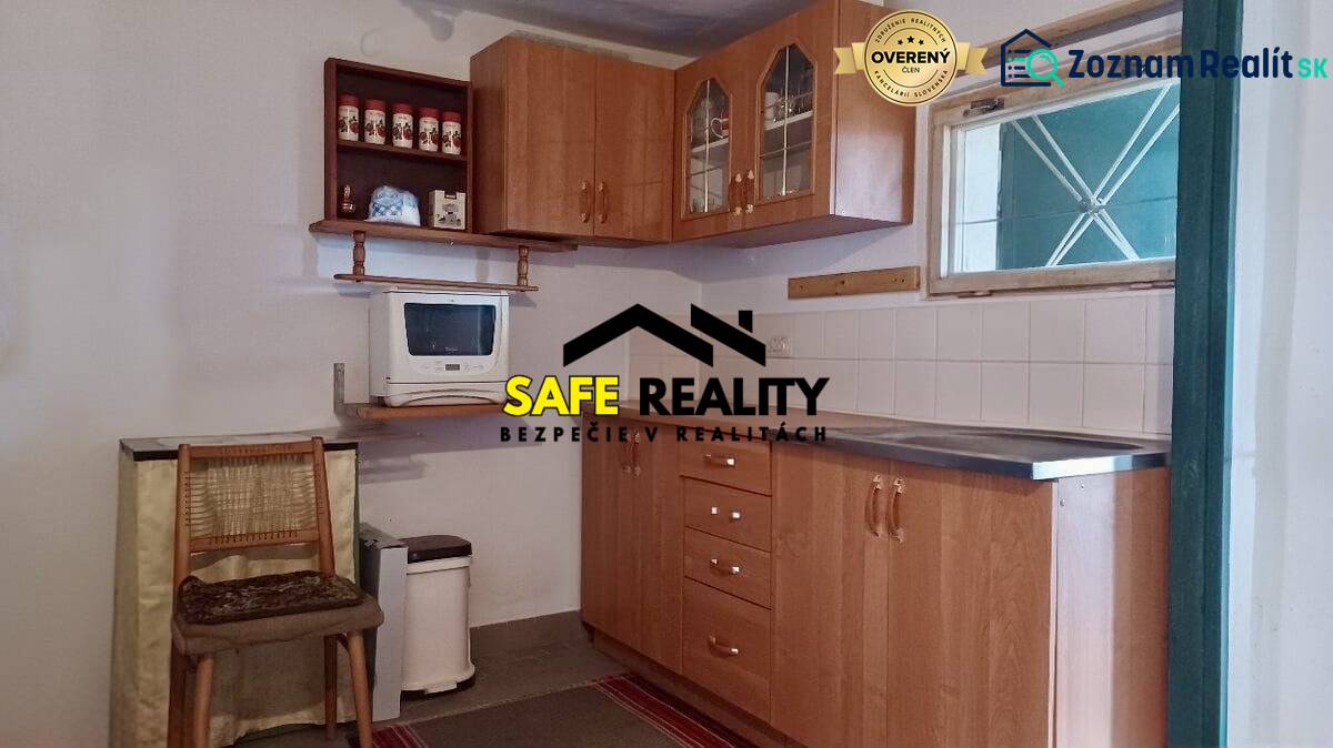 A kitchen in a cottage with wooden furniture and a microwave, floor with wooden decor.