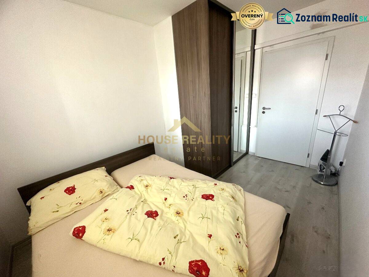 A bedroom in a 2-room apartment with a bed, built-in wardrobe, and wooden decor flooring.