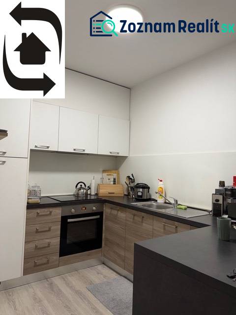 A kitchen in a 2-room apartment with a wood-patterned floor and white cabinets.