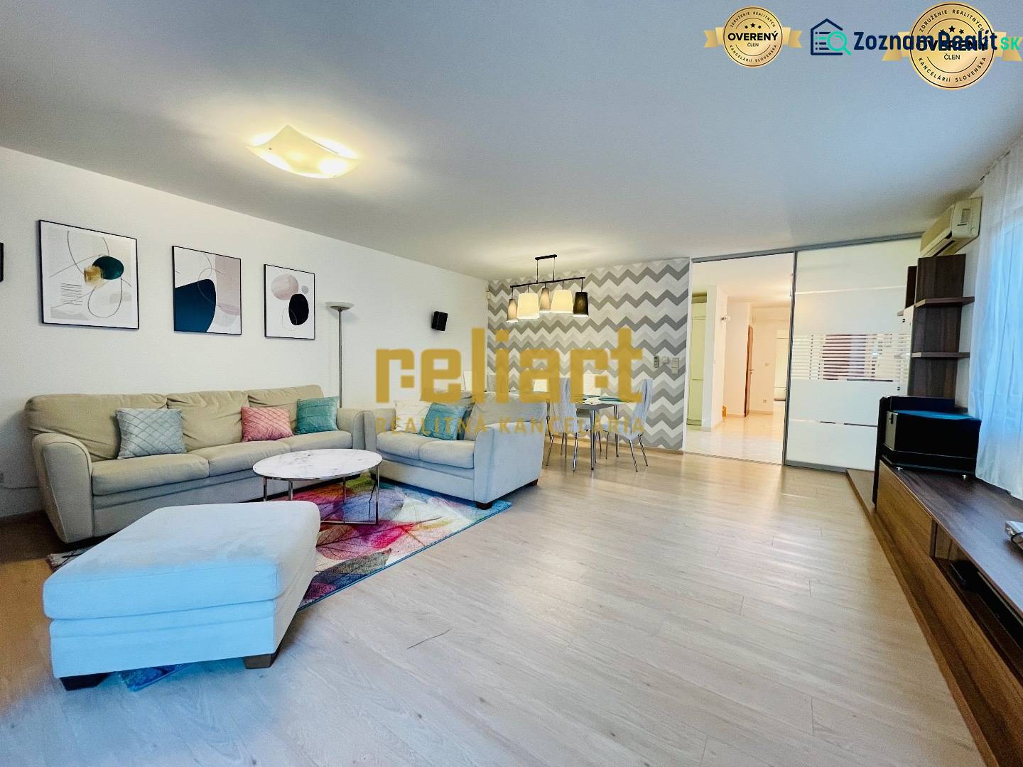 Living room in a family house with a sofa, decorations, and a wooden-patterned floor.