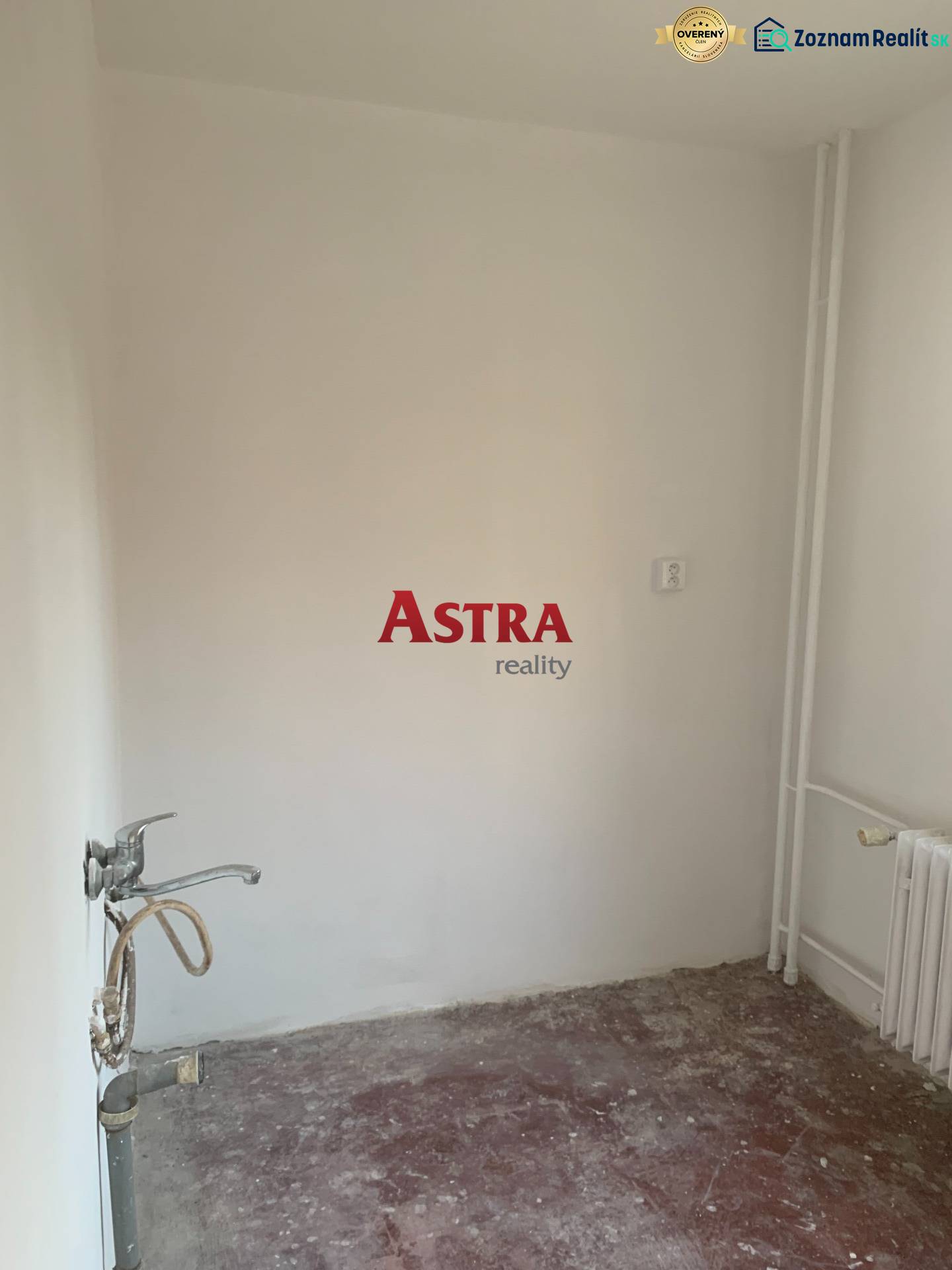 An empty room in a two-room apartment without flooring and with a sink.