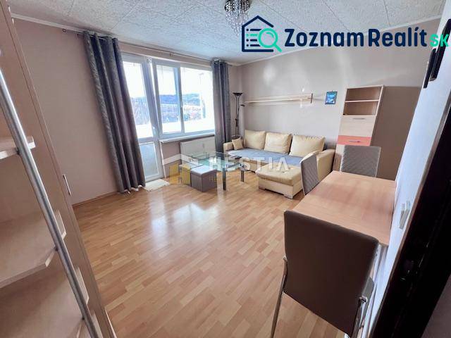 Living room of a two-room apartment with a wooden decor floor and light furniture.