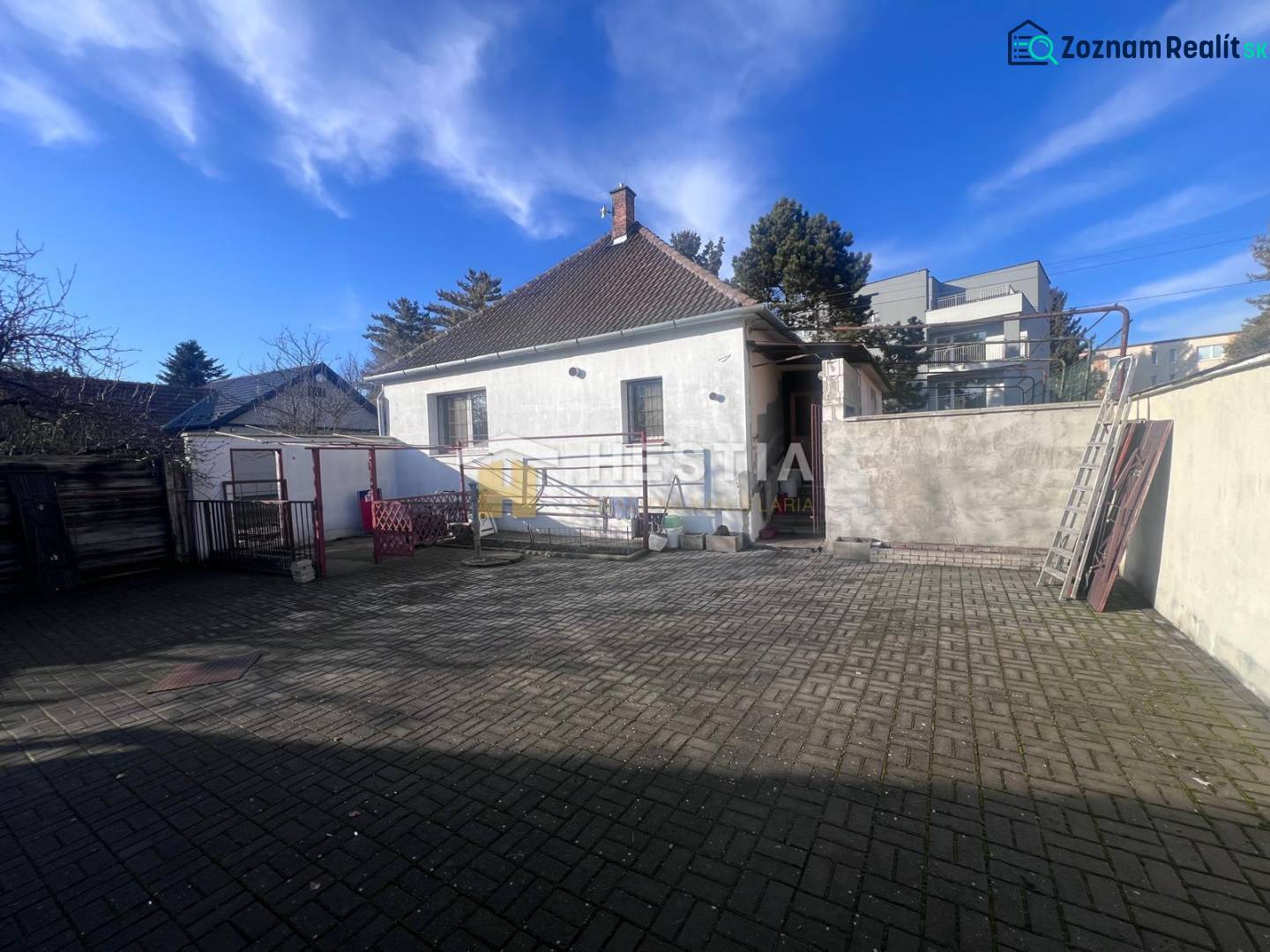 Courtyard exterior with concrete paving and a family house in the town of Senica, presented as gastro premises.
