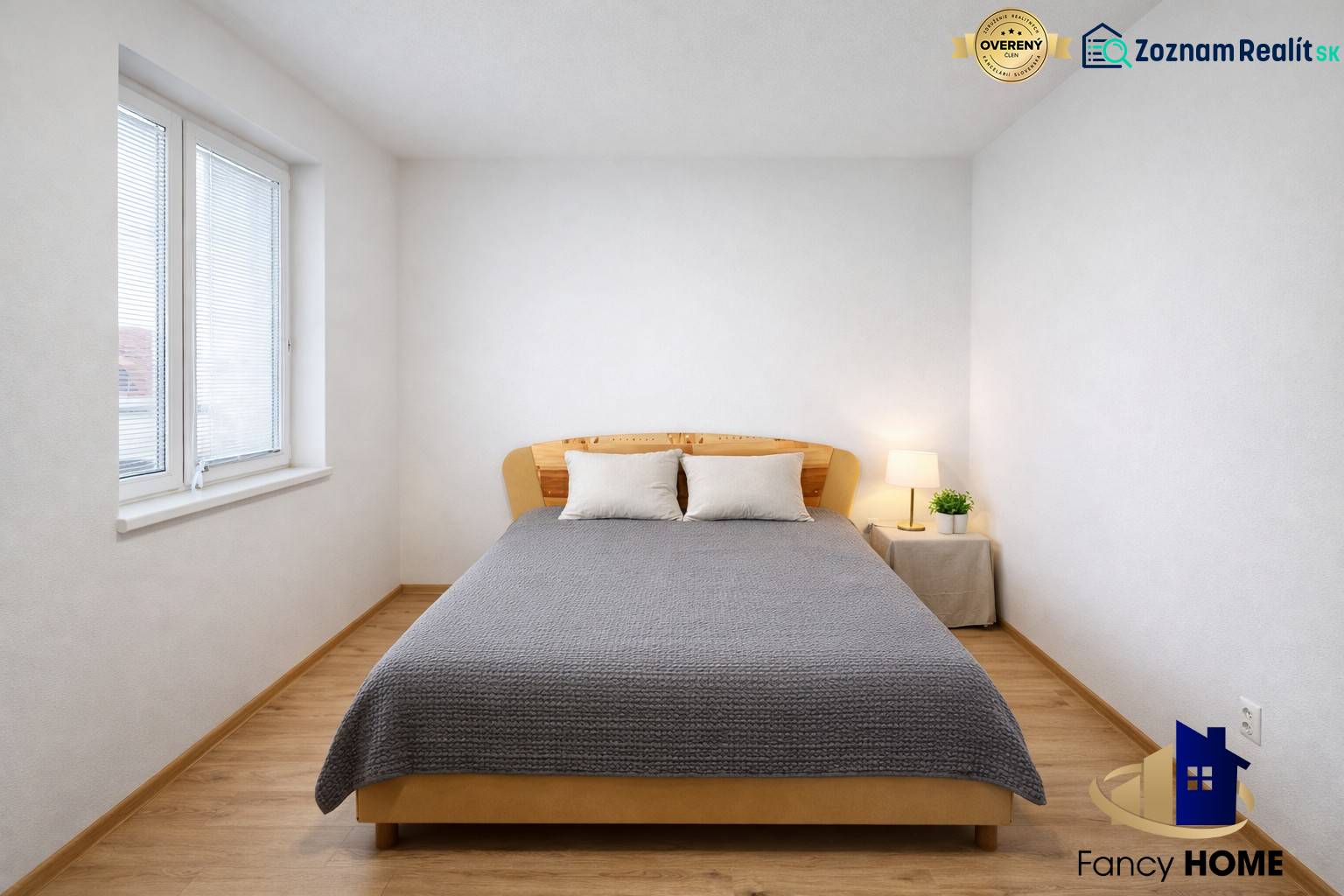 A bright bedroom with wood-patterned flooring in a 2-room apartment, decorated with a bed and a lamp.