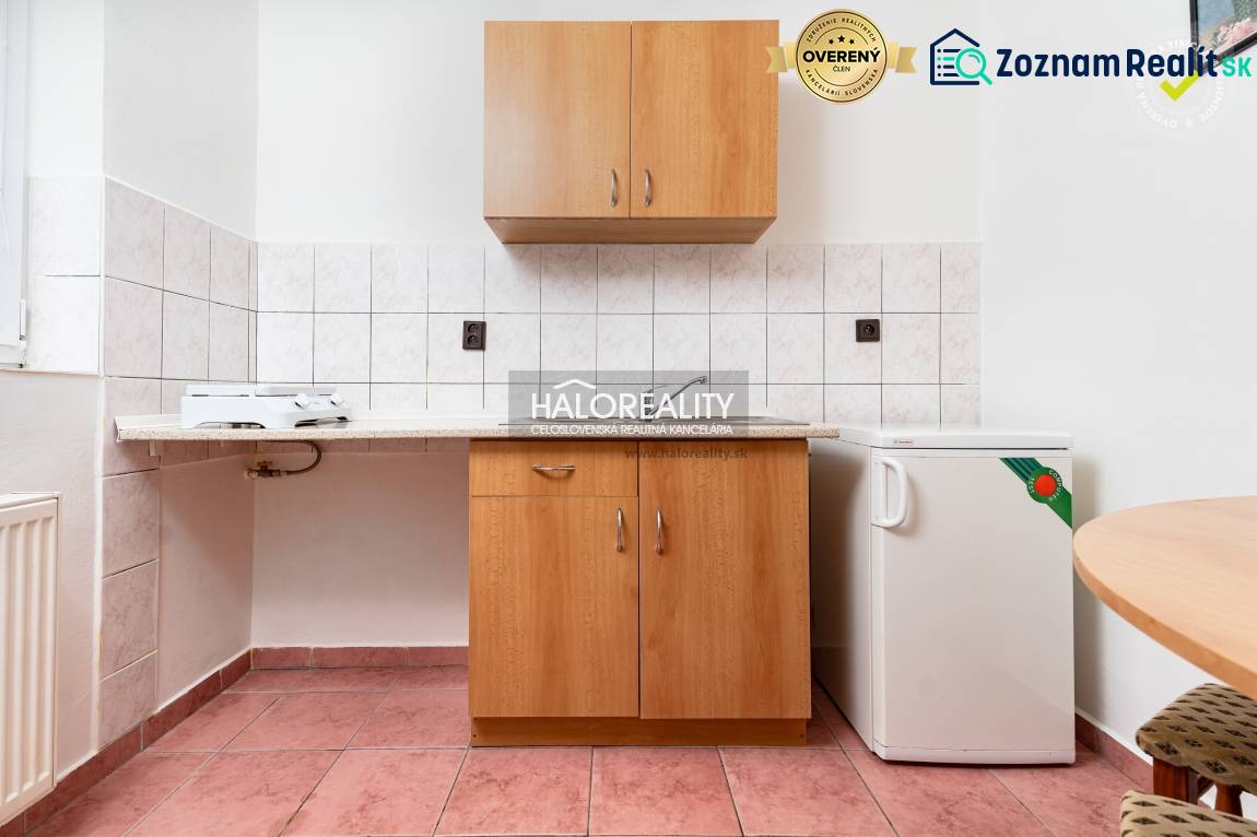 Kitchen area with tiles, cabinets, and a small refrigerator in hotels and guesthouses.