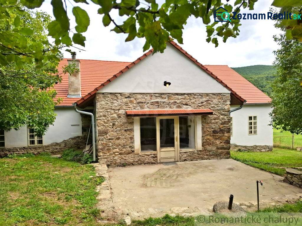 A family house in Dobroč with a stone facade, traditional roof, and a pleasant garden.