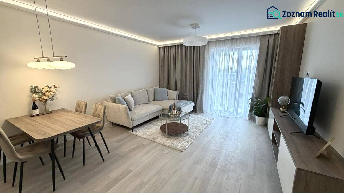 Living room in a two-room apartment with a wooden decor floor, a sofa, and a dining table.