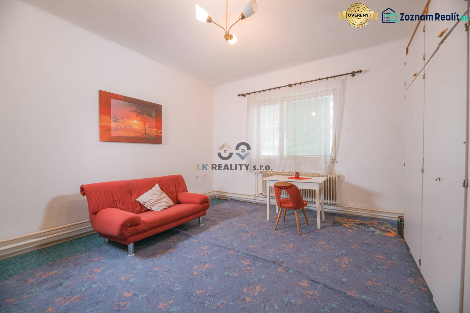 Living room in a family house with a red sofa and a table with a chair.