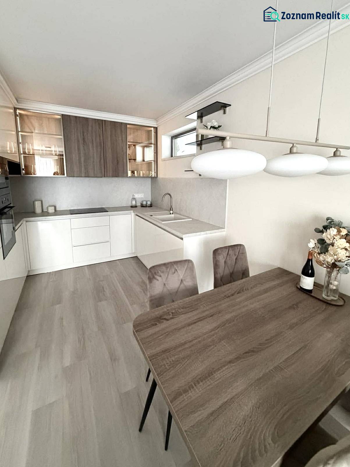 A kitchen in a 2-room apartment with a wooden decor floor, bright interior, and a dining table.
