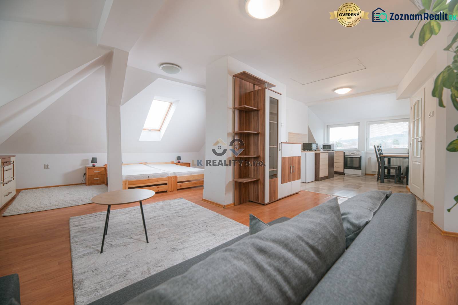 A bright interior of a 2-room apartment with a wooden decor floor and a kitchenette.