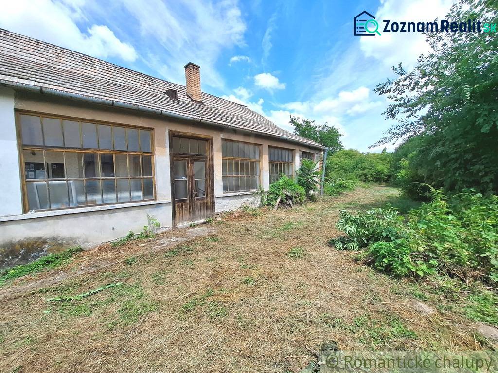 An old house in the gardens of Kamenný Most surrounded by lush greenery and trees.