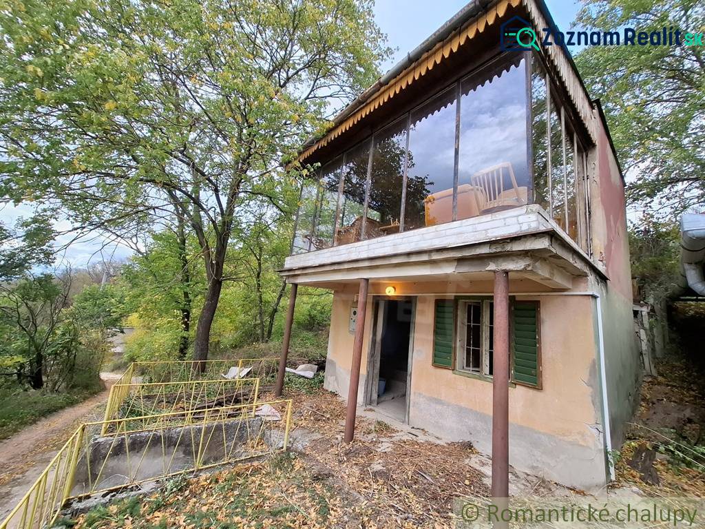 A cottage in Kamenín surrounded by greenery, with a glass terrace and a driveway.