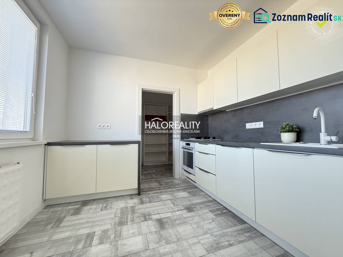 A kitchen in a 2-room apartment with a wooden decor floor and light furniture.